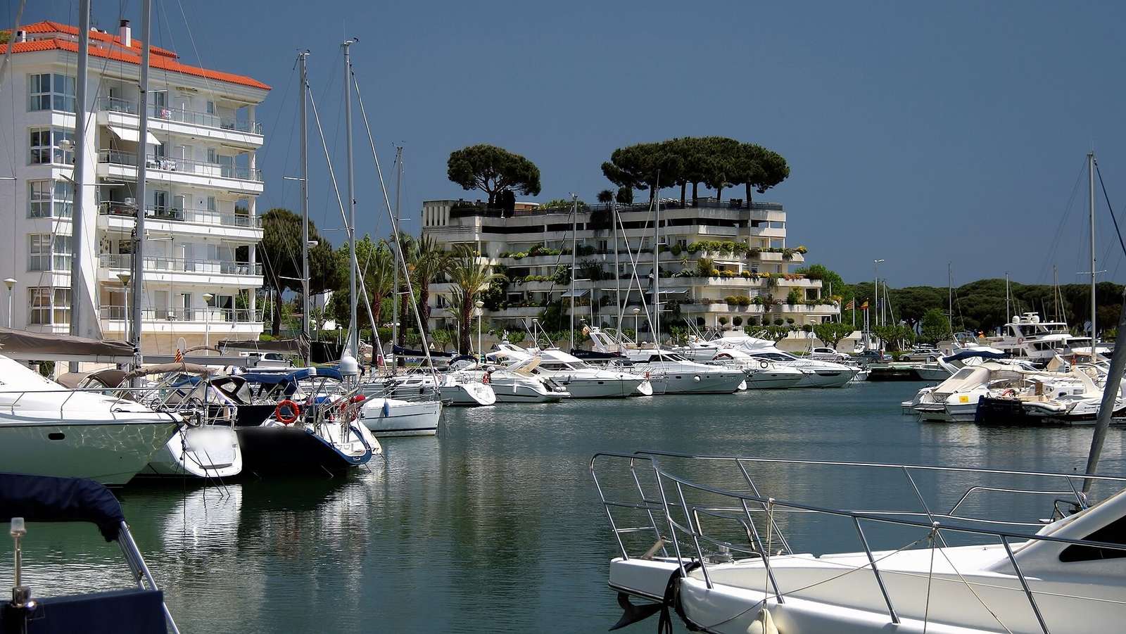 Barcos amarrados en Port d'Aro, Platja d'Aro, frente a los apartamentos y los pinos